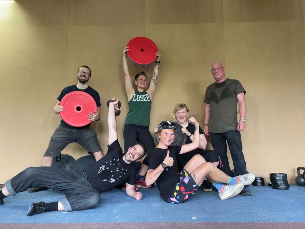 Photo of a group of people smiling and sweaty, lifting weights