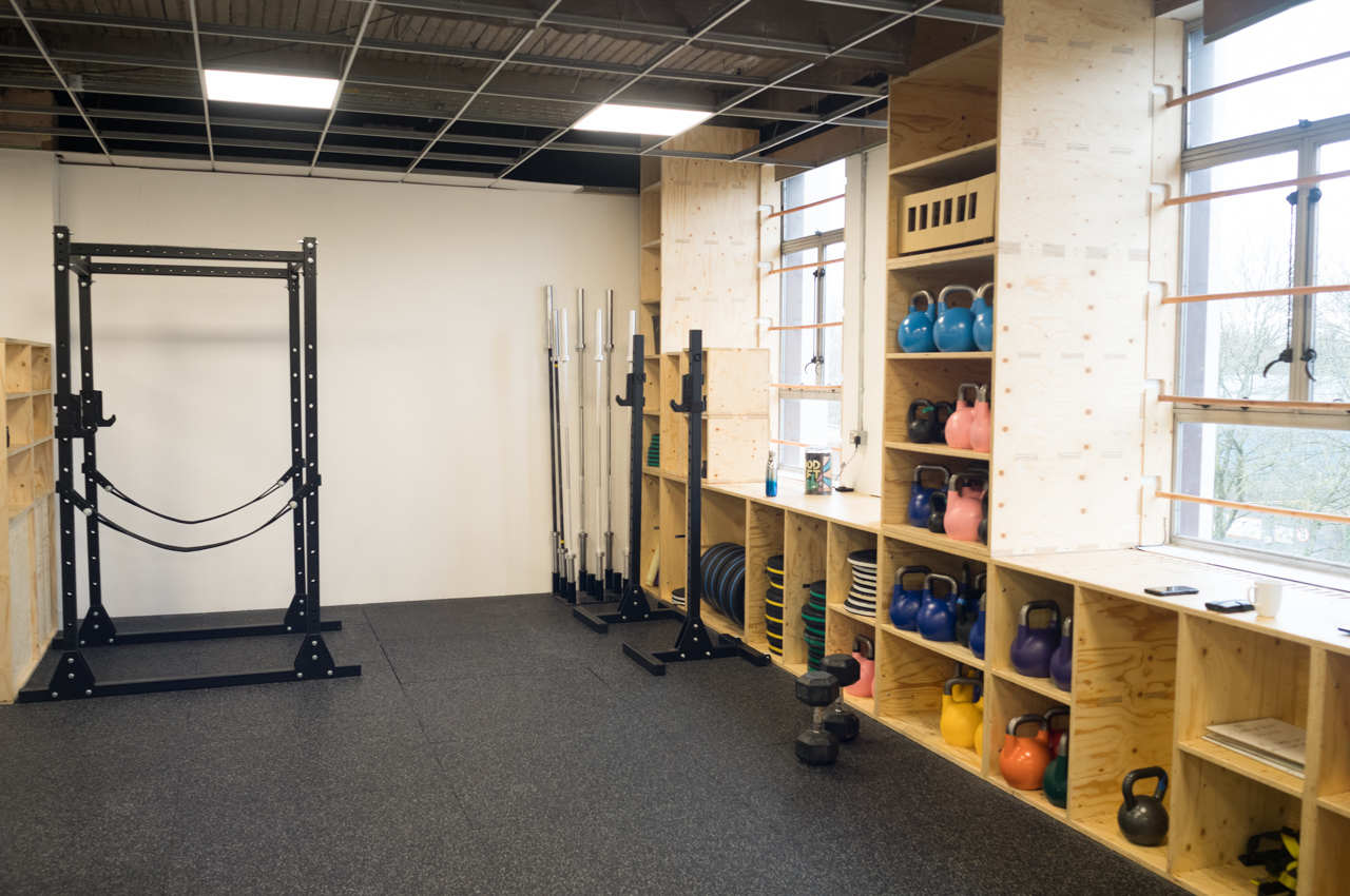 Photo of a bright gym space, with a squat rack